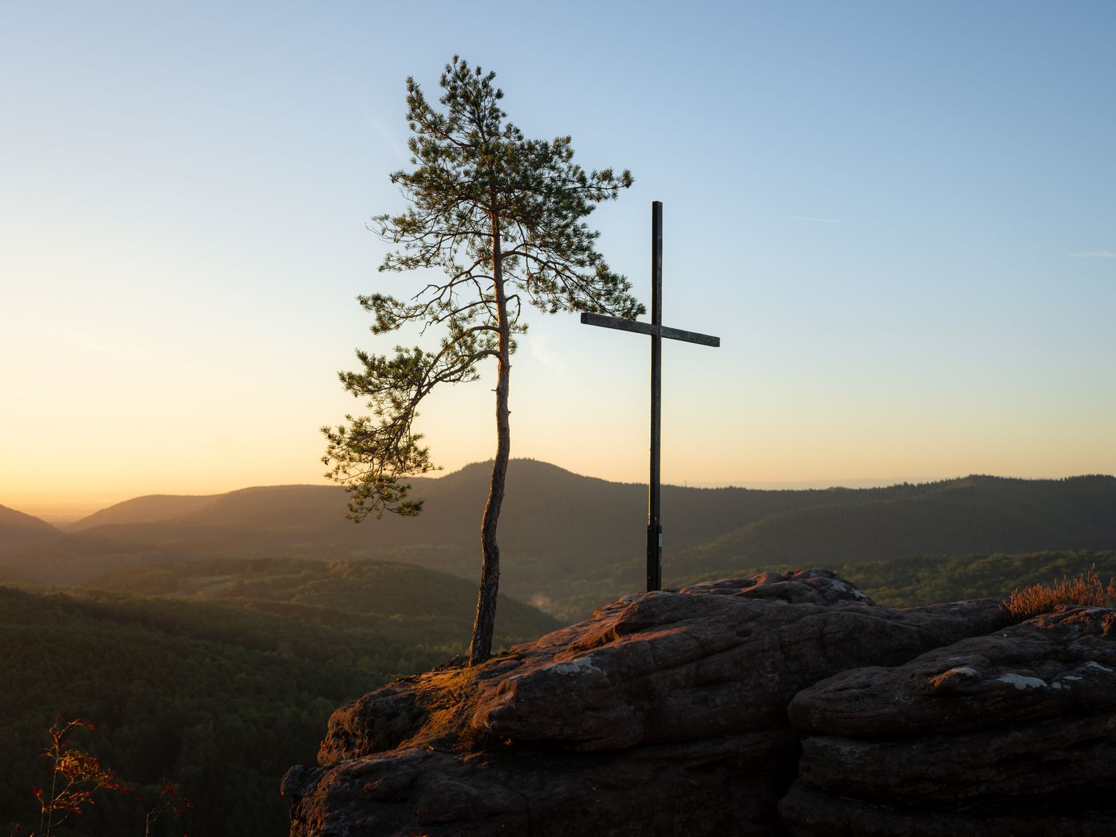 A cross on a hill at sunset